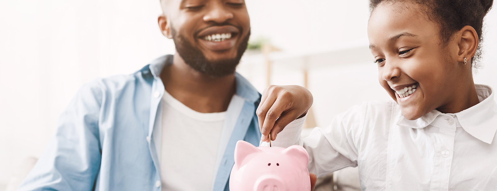 Father and daughter putting money in piggy bank