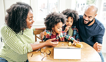 Parents with two kids at home playing.