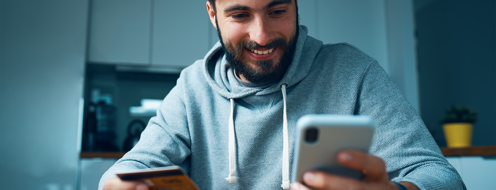 Man at kitchen table managing his debit card on mobile phone app