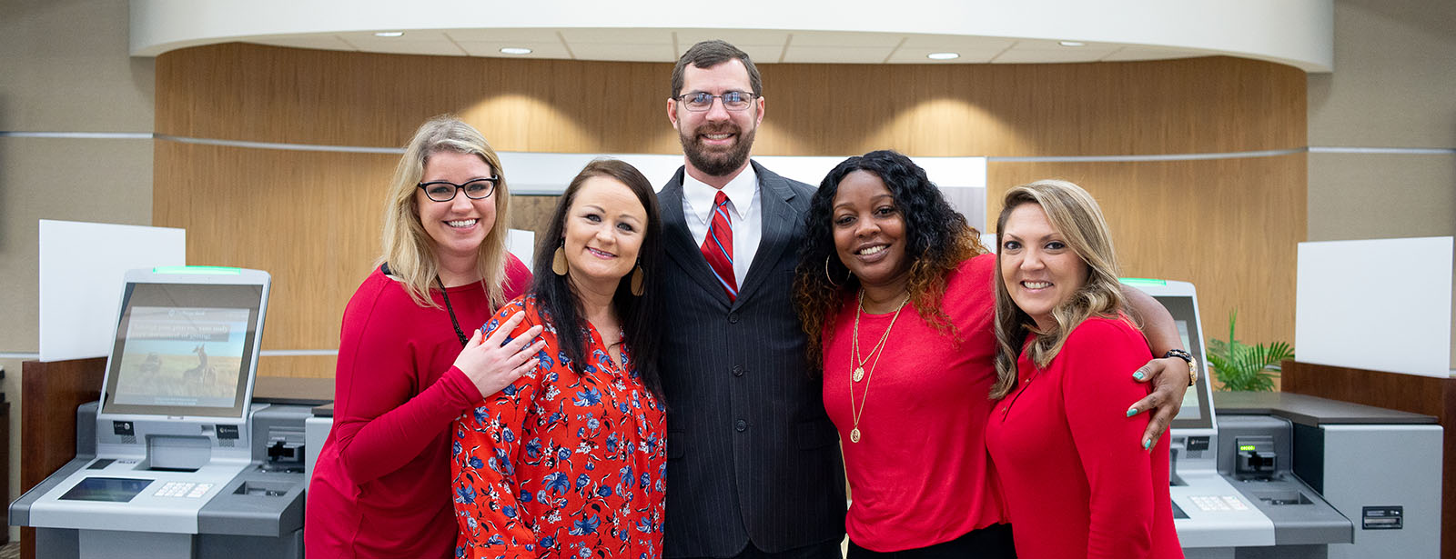 Photo of Exchange Bank's Lake Sinclair Branch Employees, smiling and embracing in the lobby.