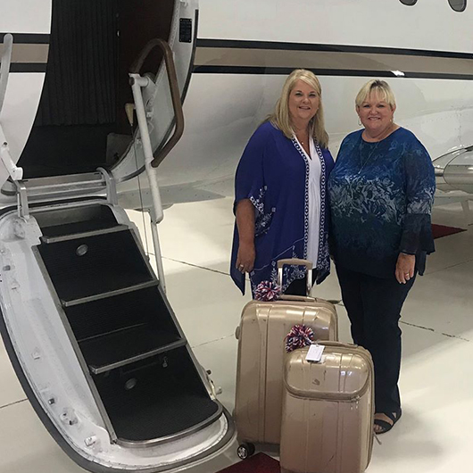 Two of the New Horizons Directors, standing in front of plane with luggage.